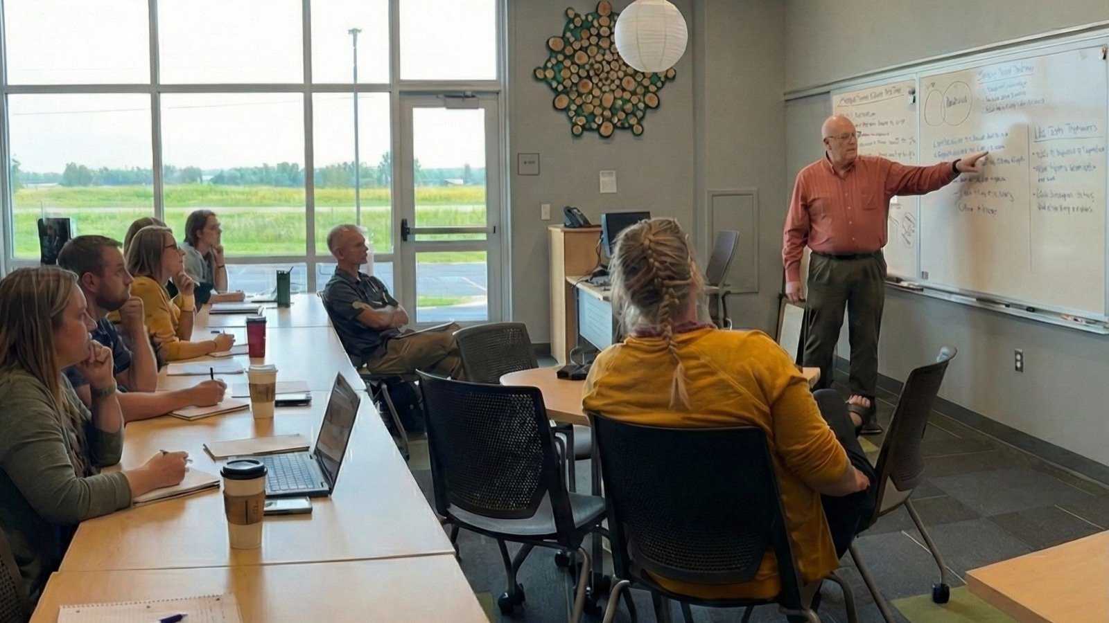 Stephen Best leading a systems workshop, pointing at a whiteboard while educators take notes